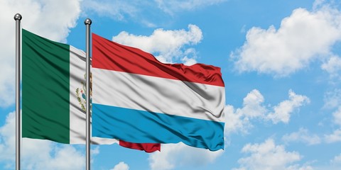 Mexico and Luxembourg flag waving in the wind against white cloudy blue sky together. Diplomacy concept, international relations.