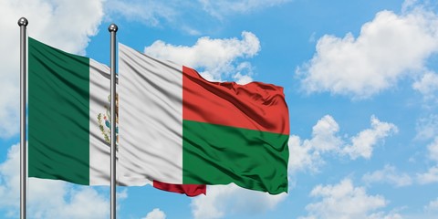 Mexico and Madagascar flag waving in the wind against white cloudy blue sky together. Diplomacy...