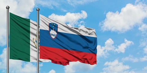 Mexico and Slovenia flag waving in the wind against white cloudy blue sky together. Diplomacy...