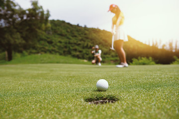 Golfer putting golf ball on the green golf, lens flare on sun set evening time.