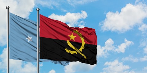 Micronesia and Angola flag waving in the wind against white cloudy blue sky together. Diplomacy...