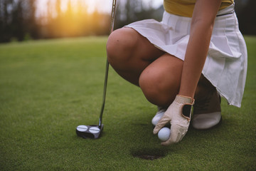 Female golfers pick up golf balls in holes on the green lawns. The girl friend is waiting for the...