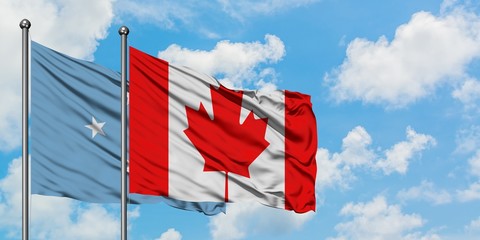 Micronesia and Canada flag waving in the wind against white cloudy blue sky together. Diplomacy...