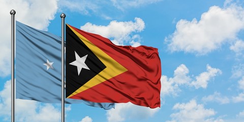 Micronesia and East Timor flag waving in the wind against white cloudy blue sky together. Diplomacy concept, international relations.