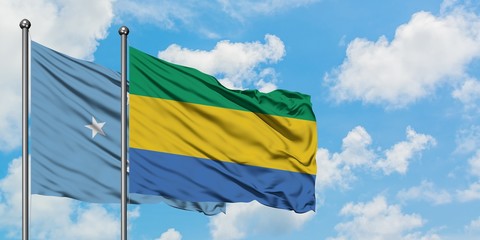 Micronesia and Gabon flag waving in the wind against white cloudy blue sky together. Diplomacy concept, international relations.