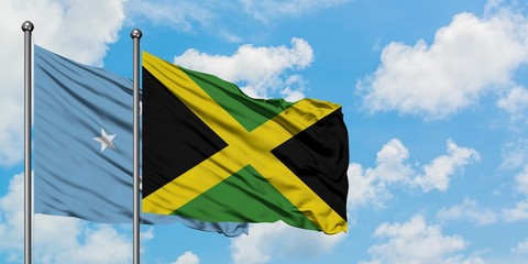 Micronesia and Jamaica flag waving in the wind against white cloudy blue sky together. Diplomacy concept, international relations.