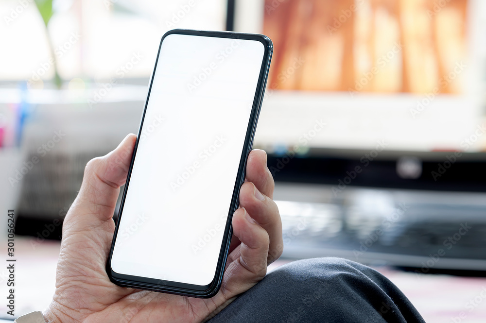 Fototapete closeup man using smartphone with blank screen while sitting at office desk, blank screen for text o