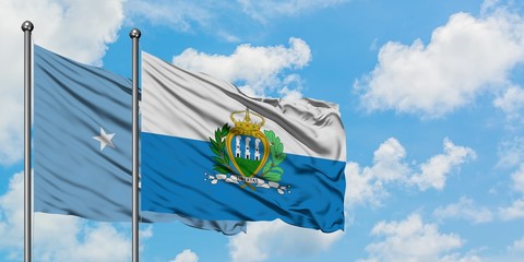 Micronesia and San Marino flag waving in the wind against white cloudy blue sky together. Diplomacy...