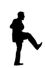 Silhouette of a backlit model posing as a businessman on a white background.  He is kicking out of frustration or fighting someone.
