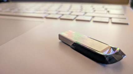 Slick usb memory on top of a laptop. Keyboard shown in background. Crisp and sharp.
