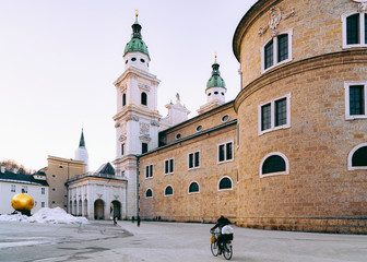 Woman on bicycle at Salzburger Dom Salzburg Cathedral in Austria in winter with snow. View of...