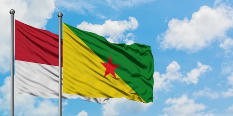 Monaco and French Guiana flag waving in the wind against white cloudy blue sky together. Diplomacy concept, international relations.