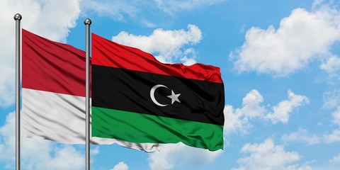 Monaco and Libya flag waving in the wind against white cloudy blue sky together. Diplomacy concept, international relations.