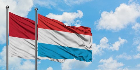 Monaco and Luxembourg flag waving in the wind against white cloudy blue sky together. Diplomacy concept, international relations.