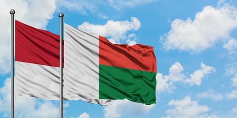 Monaco and Madagascar flag waving in the wind against white cloudy blue sky together. Diplomacy concept, international relations.