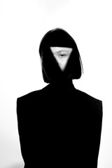 Fashionable beauty portrait. Black silhouette on white background. Girl with a spot of light on her face. 