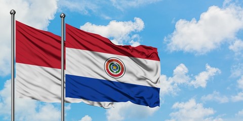 Monaco and Paraguay flag waving in the wind against white cloudy blue sky together. Diplomacy concept, international relations.