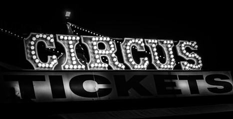 Spooky old dimly lit circus sign with light bulbs in the dark over a ticket stand in black and white. Typical view of an entrance to a circus. Concept of madness and scary. © Andres Conema