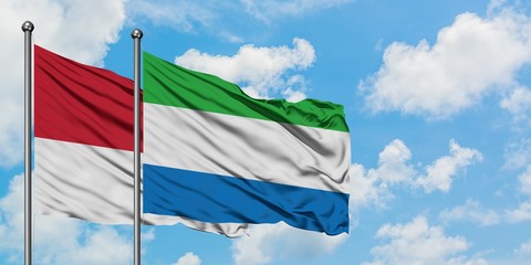 Monaco and Sierra Leone flag waving in the wind against white cloudy blue sky together. Diplomacy...