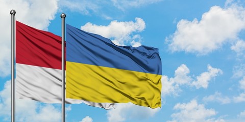 Monaco and Ukraine flag waving in the wind against white cloudy blue sky together. Diplomacy concept, international relations.