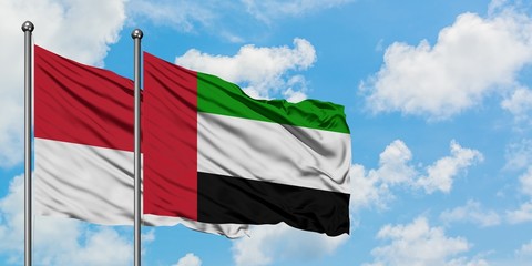 Monaco and United Arab Emirates flag waving in the wind against white cloudy blue sky together....