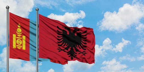 Mongolia and Albania flag waving in the wind against white cloudy blue sky together. Diplomacy concept, international relations.