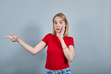 Smiling young woman in red shirt clothes showing pointing copy space with hands finger isolated on grey background, studio portrait. People religious lifestyle concept.
