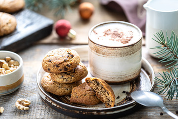 Homemade cookies with nuts and coffee in a ceramic cup on a wooden table with toys and Christmas tree branches