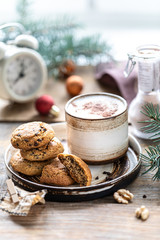 Homemade cookies with nuts and coffee in a ceramic cup on a wooden table with toys and Christmas tree branches