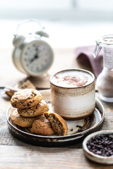 Homemade cookies with nuts and coffee in a ceramic cup on a wooden table. Time to drink some coffee. Alarm clock in the background. Breakfast
