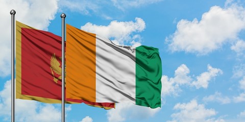 Montenegro and Cote D'Ivoire flag waving in the wind against white cloudy blue sky together....