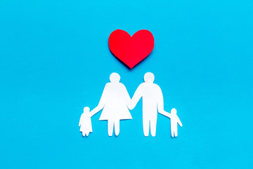 Happy family concept. Heart icon near mom, dad and childrens cutout on blue background top view copy space