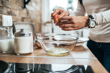 Woman separating egg yolk from white in modern kitchen, close-up.