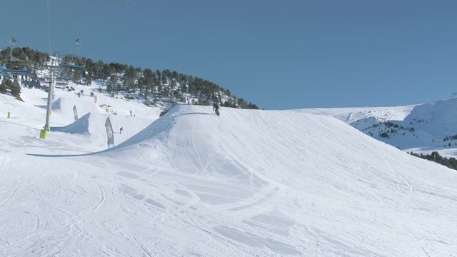 Snowboarder in Snowpark with Moving Chair Lift on Sunny Weather Day 3