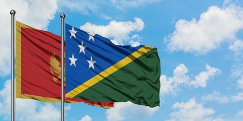 Montenegro and Solomon Islands flag waving in the wind against white cloudy blue sky together....