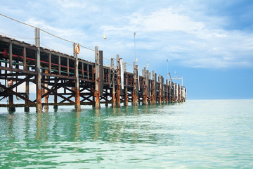 Obraz premium Wooden pier on turquoise water, blue sky, clouds background, ship wharf scenic perspective view seascape, fishing boat dock, beautiful old quay bridge, landing stage, jetty on Samui island, Thailand