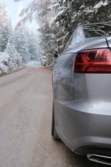 Car adventure.Winter road trip.Car on a winter mountain road.Gray car on the road in a winter snowy forest