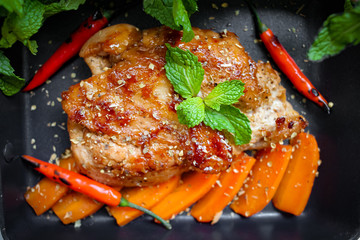Grilled chicken breast steak on black pan, roasted carrots and mint leaves decoration, healthy eating for diet program, high protein food for body building, top view, copy space