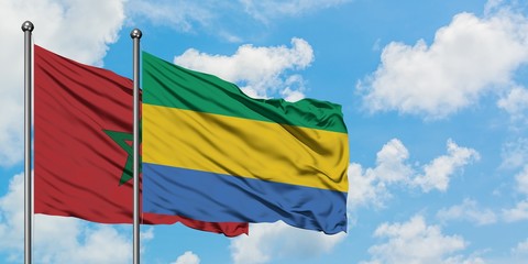 Morocco and Gabon flag waving in the wind against white cloudy blue sky together. Diplomacy...