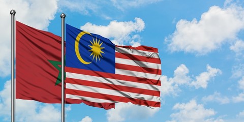 Morocco and Malaysia flag waving in the wind against white cloudy blue sky together. Diplomacy concept, international relations.