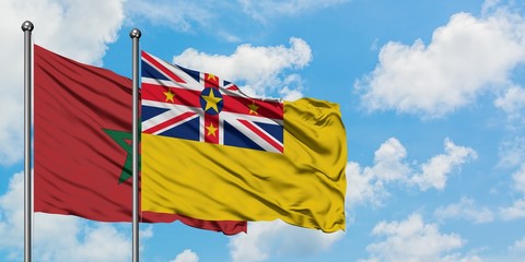 Morocco and Niue flag waving in the wind against white cloudy blue sky together. Diplomacy concept, international relations.