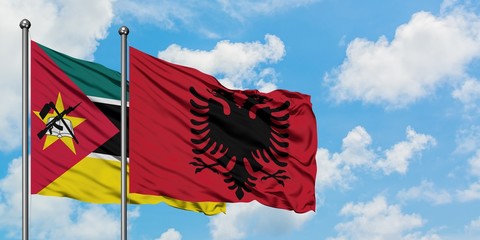 Mozambique and Albania flag waving in the wind against white cloudy blue sky together. Diplomacy concept, international relations.