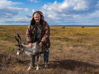 man holds a deer in the pasture