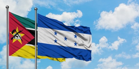 Mozambique and Honduras flag waving in the wind against white cloudy blue sky together. Diplomacy...