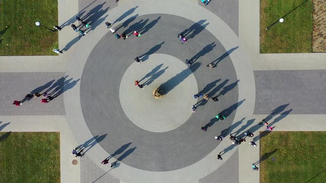 People and Shadows Moving on Circular Square, Top Down Bird Eye Cinematic Ascending Aerial View