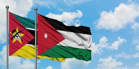 Mozambique and Jordan flag waving in the wind against white cloudy blue sky together. Diplomacy...