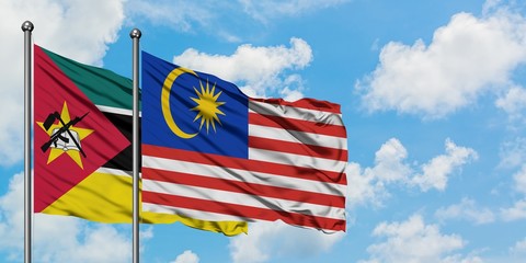 Mozambique and Malaysia flag waving in the wind against white cloudy blue sky together. Diplomacy concept, international relations.