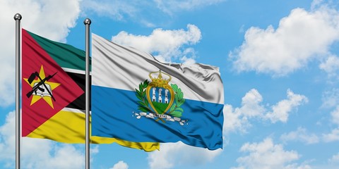 Mozambique and San Marino flag waving in the wind against white cloudy blue sky together. Diplomacy...