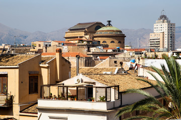 Palermo, Italy, September 19, 2019: Aerial view of the roofs of the city with a building with a dome in the background and a skyscraper and mountains in the background