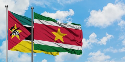 Mozambique and Suriname flag waving in the wind against white cloudy blue sky together. Diplomacy concept, international relations.
